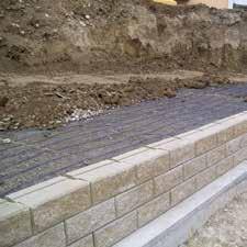Foundation The wall is built on a simple shallow concrete levelling strip or compacted stone foundation below the wall face.