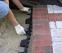 The bedding sand needs to be pulled away from the edge of pavement so the edging can be installed.