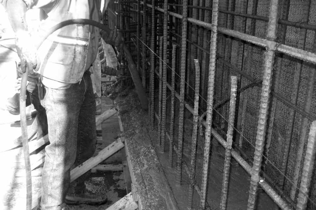 WALL Photo illustrates shotcrete structural foundation wall being applied against / waterproofing system installed on wood