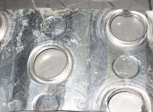 When the sample was removed from the cleaning solution, white precipitate had formed around the pockets of corrosion.