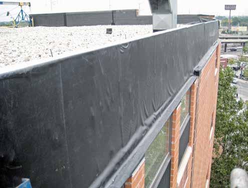 roof. The tie-in of the new roofing flashing consists of a fully adhered EPDM flashing membrane extending over the wood blocking and down the back face of the parapet, and adhering to the existing
