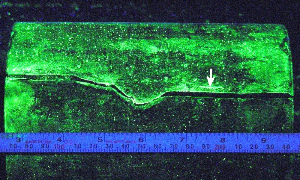 Figure 2 Wet fluorescent magnetic particle indication, arrow, at a secondary crack.