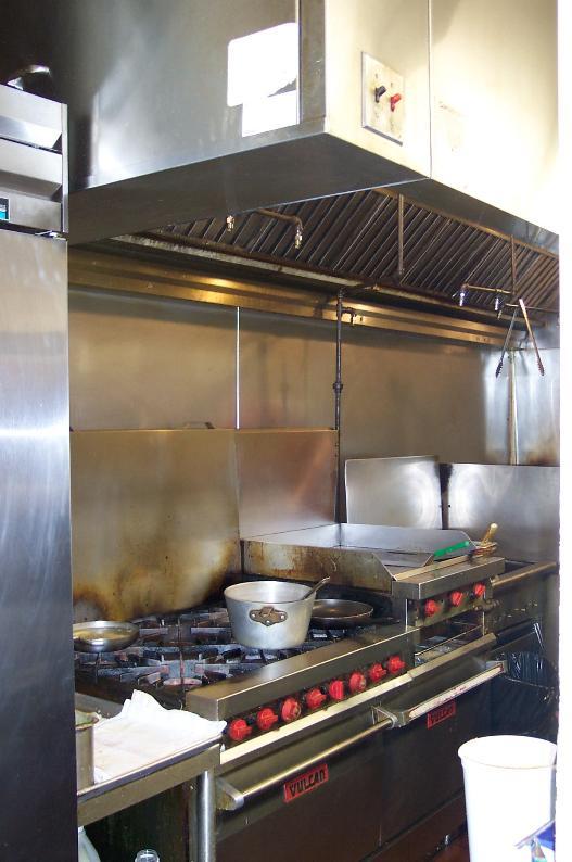 The kitchen contains an exhaust hood above the griddle and fryers.