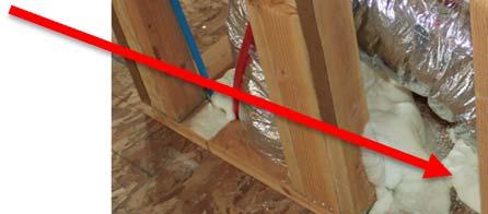 This photo shows a draft stop cut from OSB to fit around two ducts going up through a