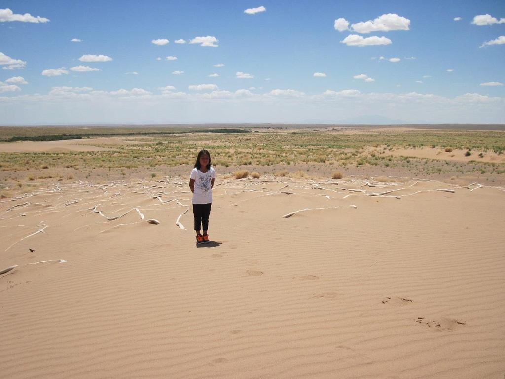Navajo girl on sand dune that buried her toys when she left them on a windy day-