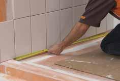 Immediately clean away any excess setting material. Install adjacent tiles on the shower base.