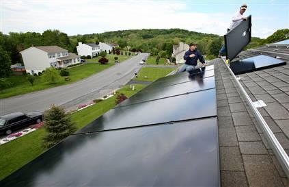 A worker installs solar panels on the roof of a home in Newburgh, N.Y.