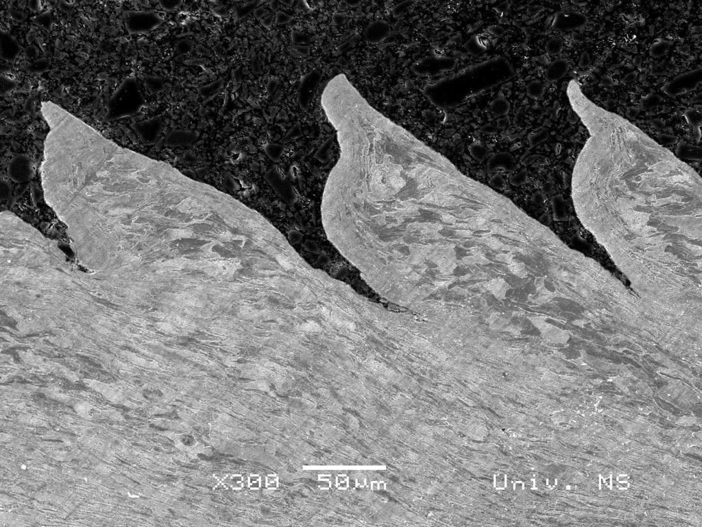 Slika 1 prikazuje poprečni presek strugotine, na elektronskom mikroskopu, pri obradi materijala novim alatom, dok je na slici 2 prikazan poprečni presek strugotine pri obradi materijala pohabanim