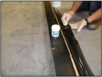Using a bristle broom to firmly adhere the membrane sheet to the wall and roof deck. Refer to the Outside Corner or Roof Edge Details for instructions on terminating the edge of the membrane.