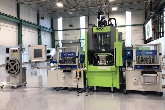 Upstream of the injection process there are a strip uncoiler, a press module and a processing module for tapping a thread; downstream there are quality controls, laser marking and another press