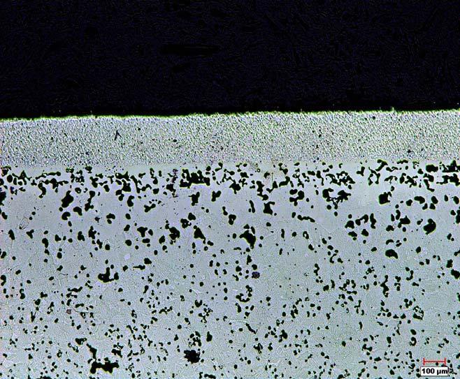 Figure 8. BNi-9 Cr 3 C 2 coating on P/M steel (bottom) with a braze/carbide ratio of ~1.5. Increased spherodization and growth of pores in the P/M steel near the coating.