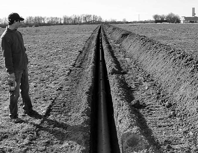 Figure 8. Robin Frazier (NRCS) checks out a pipeline. Land leveling improves the flow of irrigation water by grading to either a very gentle slope or no slope at all.