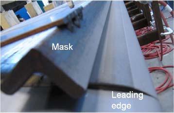 Figure 11: Blade coating process To protect the portion of the blade adjacent to the Titanium sheath an iron fixture was clamped to the blade to shield the area from the HVAF spray.