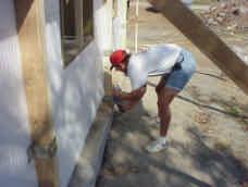 Once the wall has been leveled and checked for square, use low expansion foam adhesive to glue the base of the wall to the slab or footing.