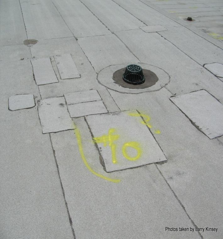 Photo # 17 Description [ 2 story ] This digital photo shows and area # 10 marked on roof near a roof drain on the west side of upper roof.