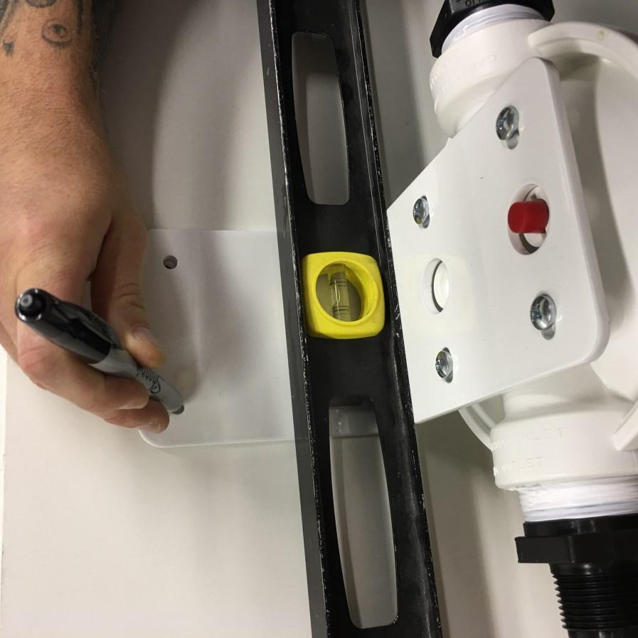 Mark the hole locations on the wall using a marker or pencil while holding the filter housing