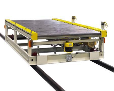 Heavy duty chain driven live roller conveyor runs on a floor-mounted track from foreground conveyor to discharge conveyor shown.