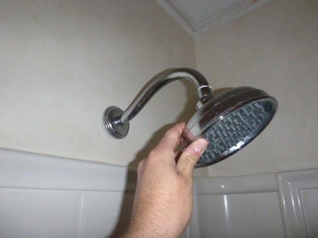 The shower body and faucet is loose behind the shower enclosure wall.