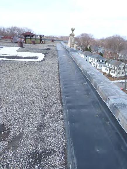General roofscape showing deteriorated vent hoods, patches in built up roofing, & various