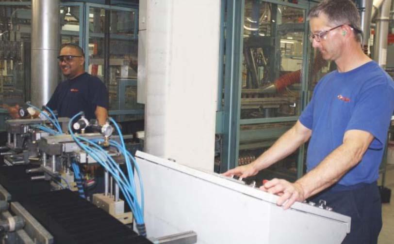 Eldwin Soto and Tim Mertz monitor the automated machinery that inserts groups into battery cases at