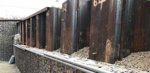 The section if the steel sheet piles and partly completed gabion cladding with 20/40mm gravel infill to the in-pans of the sheet piles behind the gabions.