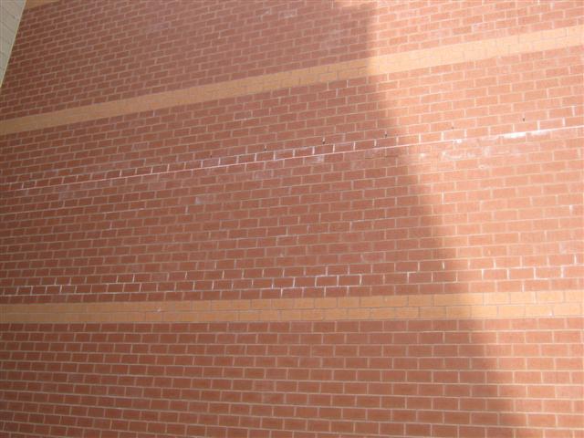 The second issue is similar to the first item but involves the visible efflorescence in the exterior brick at the relief angles on the building.