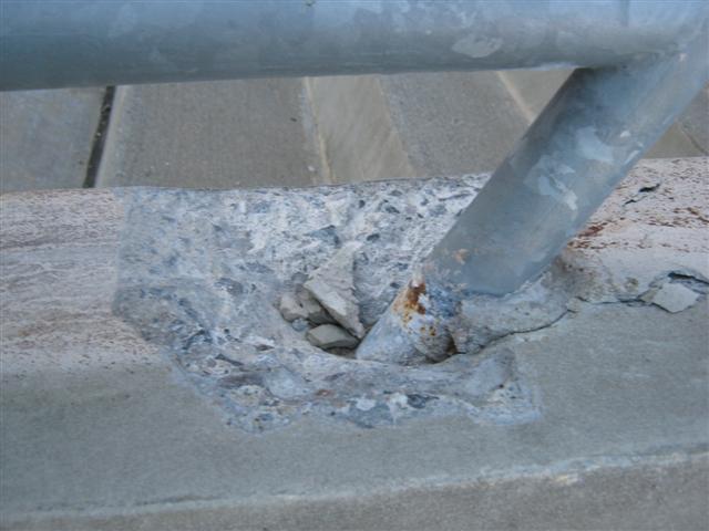 There is severe cracking and spalling of the concrete around the vertical posts of the railing system.