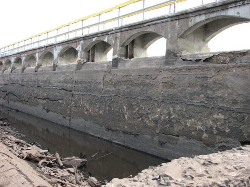 erosion throughout the spillway and sluiceway aprons, and at the spillway slab Spalling of the concrete slabs at the existing railing post locations and at a few locations at the underside of the