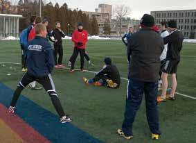 With snowbanks lining Tindall turf field at Queen s University, Kingston coach Colm Muldoon gives instruction to his players as the team opens training camp