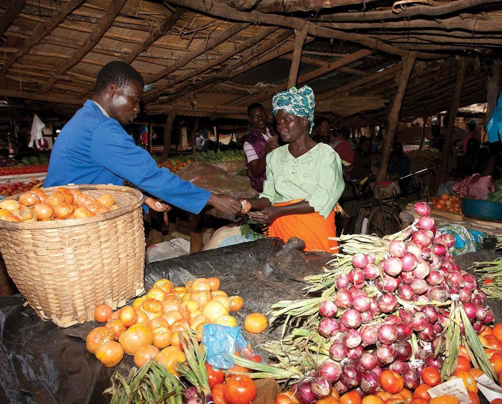Malawi - Mchinji District. One of the beneficiaries of the Social Cash Transfer Programme, selling tomatoes to a farmer at Mchinji Town market. FAO/Amos Gumulira.