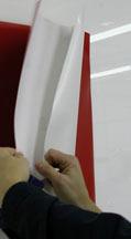 Hold the bottom edge of the graphic smooth and taut, away from the application surface with one hand and squeegee