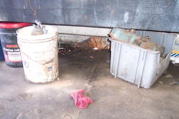 Within the workshop, several five (5) gallon oil containers were noted below the work bench. Staining is visible on the ground surrounding this area (Figure 2.6).