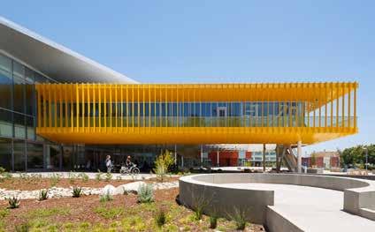The yellow metal panels reflect the school color. An exterior walkway is shaded by perforated metal panels. The column-free area beneath the skybox.