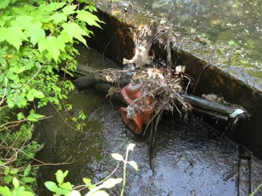 39. Facility 201. Looking at maintenance valve in weir wall currently covered in debris.